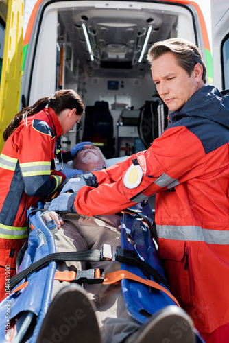 Selective focus of paramedics standing near elderly patient on stretcher and ambulance car © LIGHTFIELD STUDIOS