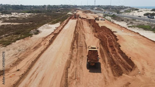 Aerial view of heavy machinery, Articulated truck moving dirt on a new road construction site, heavy equipment top down footage of dump truck
