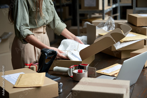 Closeup view of female online store small business owner seller entrepreneur packing package post shipping box preparing delivery parcel on table. Ecommerce dropshipping shipment service concept. photo