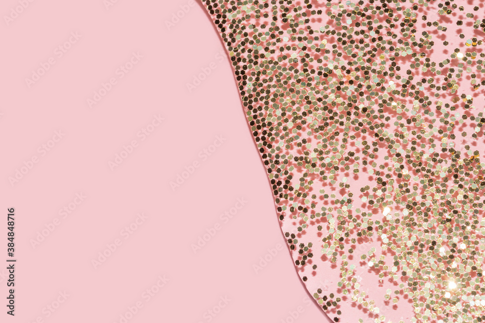 Φωτογραφία transparent liquid with gold glitter pouring over a pastel pink background
