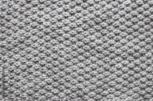 The texture of the woolen knitted gray sweater. Close-up