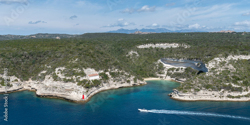 Panorama the bay and cliffs from above. Yacht sails in the center. In the background mountains and sky with clouds