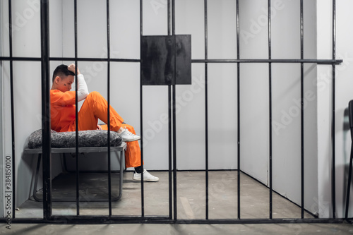 Konstfotografi Solitary cell with a criminal in an orange robe in an asian prison