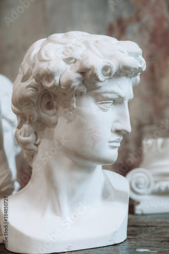 Plaster ancient greek sculpture, head of hero on wooden table.