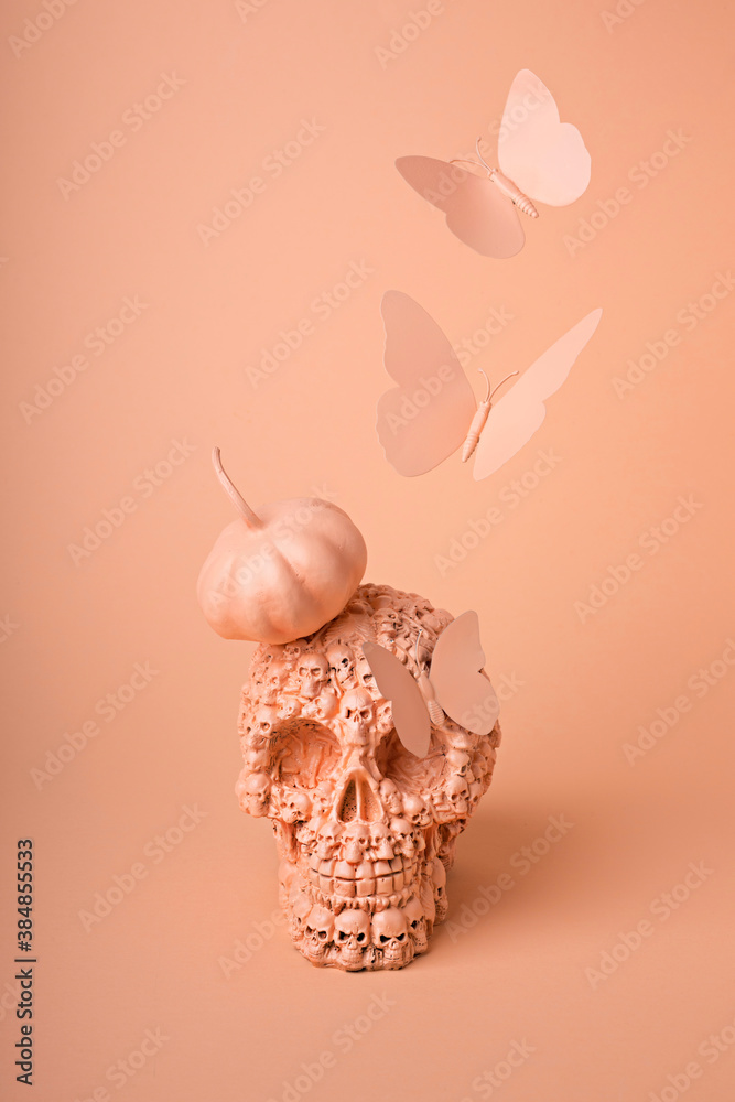 Minimal layout made with skull, butterflies and pumpkin on orange background. Creative Halloween concept. Magic surreal image, witch ritual atmosphere.