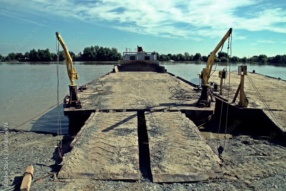 Fototapeta premium Una vieja barcaza en la orilla del río Danubio a la espera de ser cargada. Delta del río Danubio al amanecer cuando pasa cerca de Nufaru, Rumania.