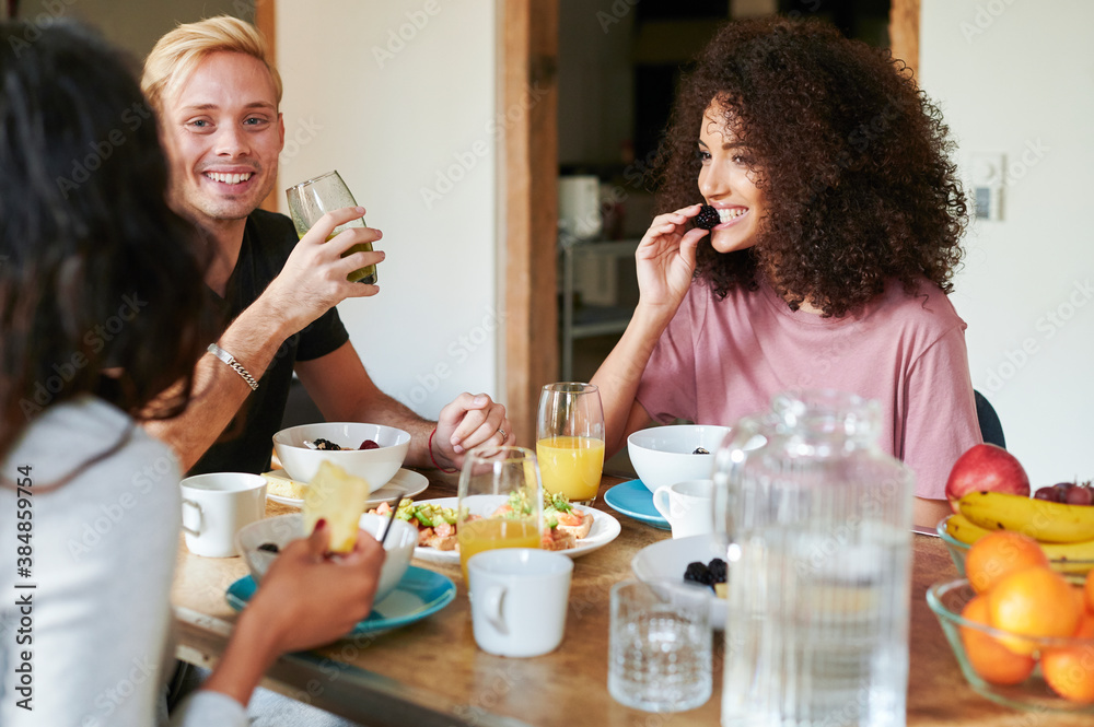 Friends smiling and talking over breakfast Friends smiling and talking over breakfast