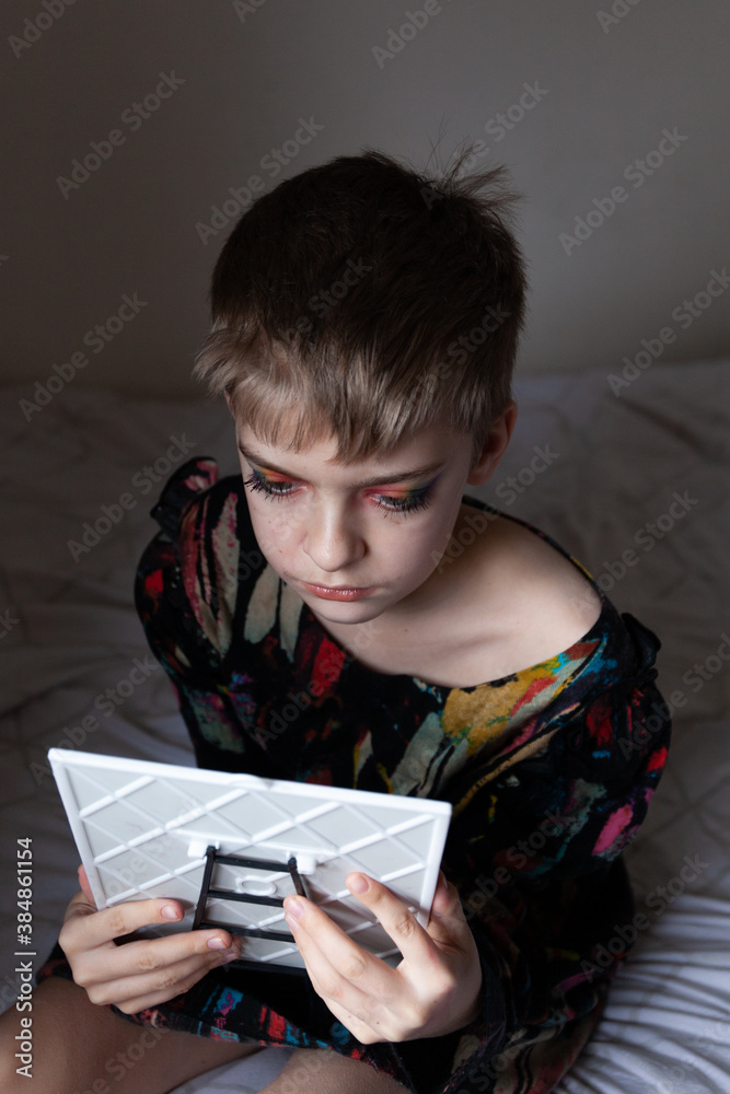 A boy checks his make up in a mirror. A boy checks his make up in a mirror.
