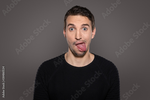 crazy smiling man having fun while show his tongue and having a grotesque face with humor grimacing