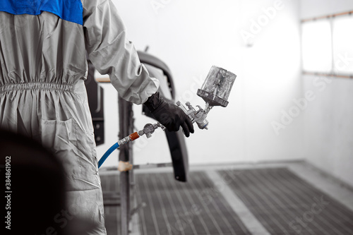 close-up photo of male hands holding machine for painting car, he is ready to work. cropped man in protective uniform