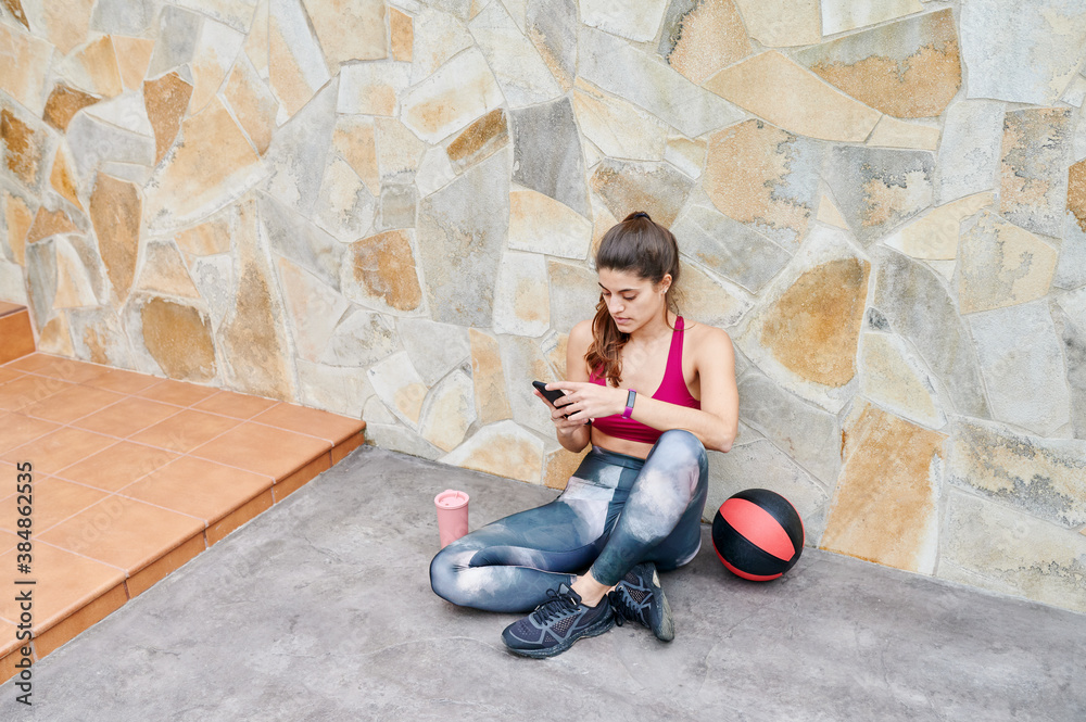 Woman using her phone during a workout break Woman using her phone during a workout break