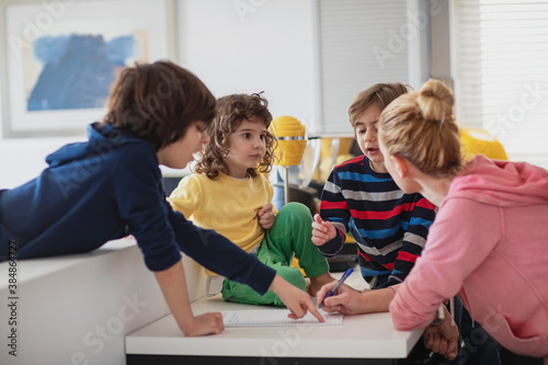 Young woman creating a shopping list for grocery with some suggestions from her kids... photo