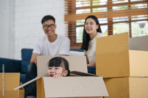 Portrait of happy Asian family moving to new house with cardboard boxes and playing cardboard box