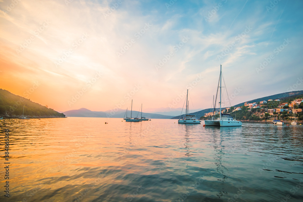Beautiful sunset on the sea, in a Marina with yachts and catamaran, against the background of mountains. Background for an ad or presentation