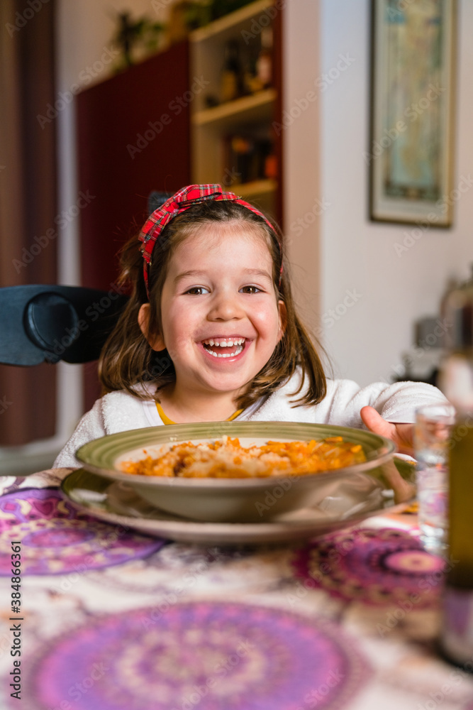 Cheerful girl eating pasta with cheese at home Cheerful girl eating pasta with cheese at home