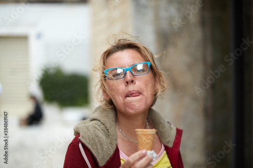 Mature attractive woman eating ice cream while exploring the historical city during her vacations © Artur Nyk
