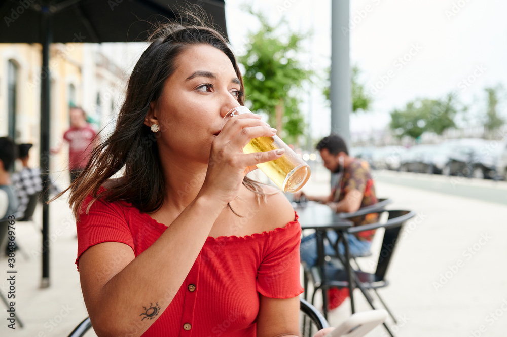 Young woman drinking a beer at a sidewalk bar Young woman drinking a beer at a sidewalk bar