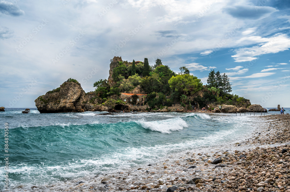 Wunderschöner steiniger Strand mit türkisblauem Wasser und großen Wellen vor der Isola Bella auf Sizilien