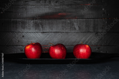 Red Apples in front of black wooden Wall