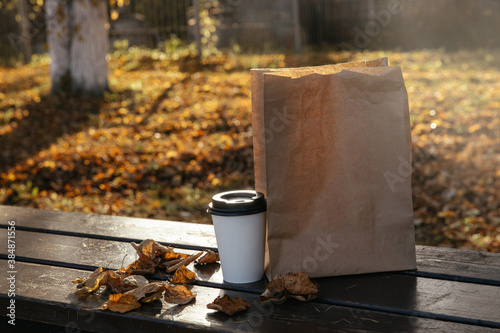 paper bag and a Cup of coffee lie on a bench in an autumn Park