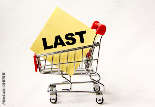 Shopping cart and text last on yellow paper note list. Shopping list, business concept on white background.