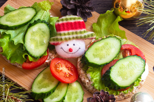 hristmas snacks, vegetarian sandwiches with vegetables and cheese. Children's menu, funny food, face, snowman. New year's food