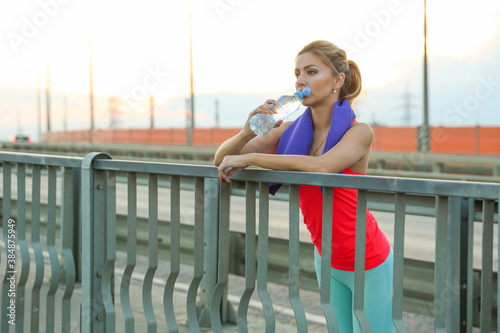 beautiful girl athlete drinks water after playing sports. woman athlete with bottle of water