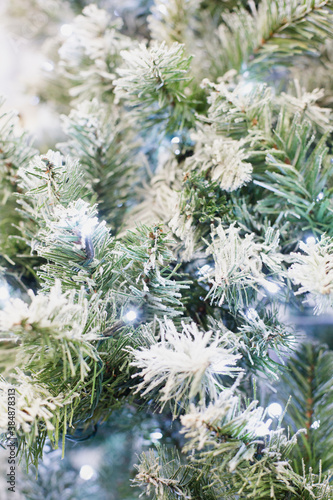 artificial green fir tree under snow with garland close-up as christmas background.