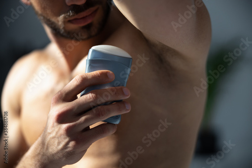 Close up shot young handsome man applying deodorant