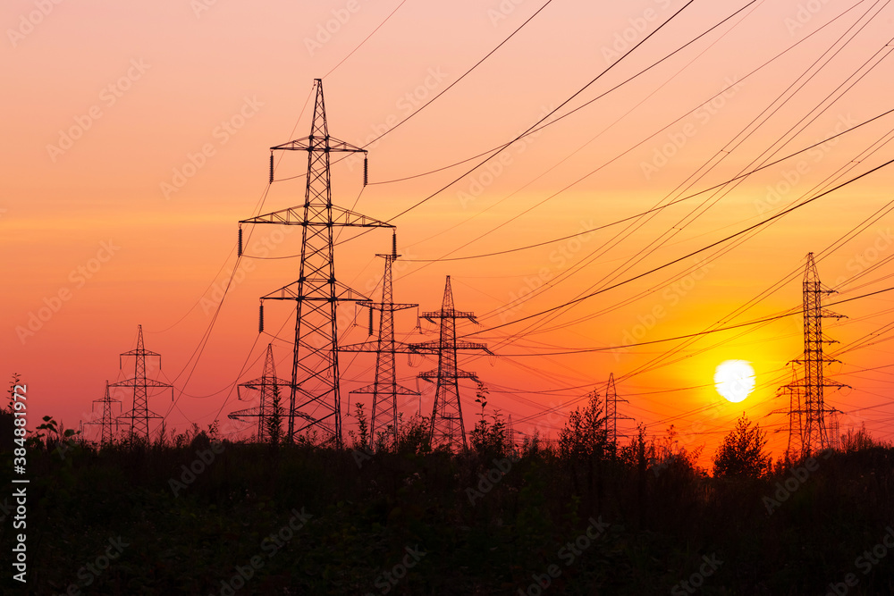Fototapeta premium Electric power transmission lines. High voltage post. Industrial landscape. Electricity pylon at sunset sky on the background. Electric distribution station