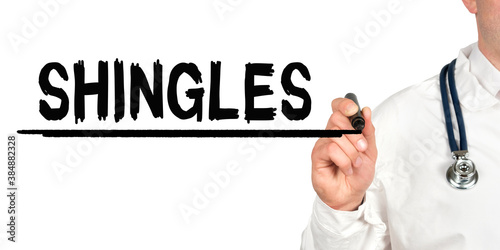 Doctor writes the word - SHINGLES. Image of a hand holding a marker isolated on a white background.