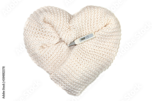 Heart made of white knitted wool and an electronic thermometer showing the temperature of a healthy person.