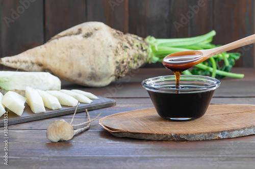 Bild auf Leinwand Sugar beet molasses in glass bowl with fresh sugar beetroot plant, healthy food,