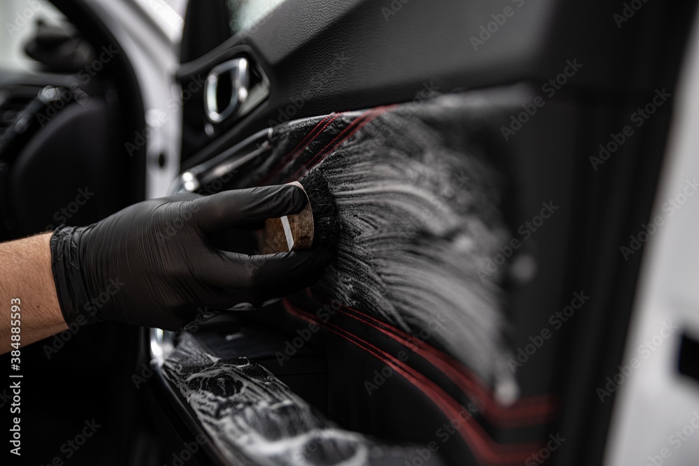 Car detailing studio worker cleaning leather car interior upholster - obrazy, fototapety, plakaty 