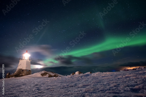 Polar light during the cold night. Marvelous light dancing in the sky. Lighthouse with the polar light. Evening in the Lofoten.