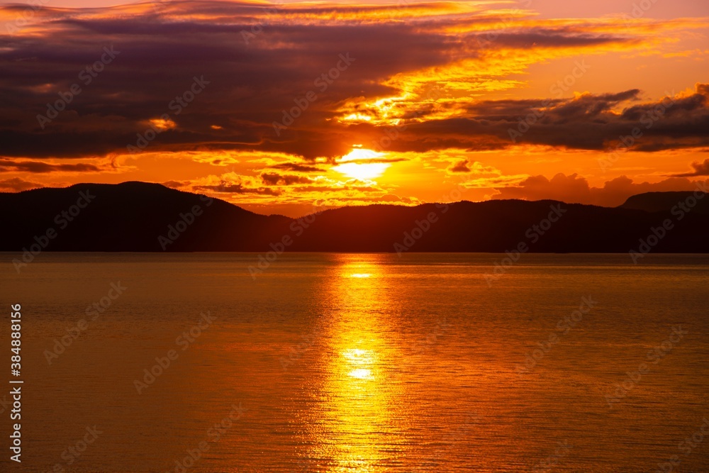 Sunset over the ocean water with the Alaskan Coast in silhouette
