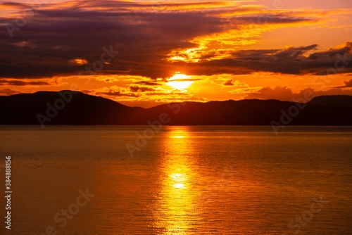 Sunset over the ocean water with the Alaskan Coast in silhouette