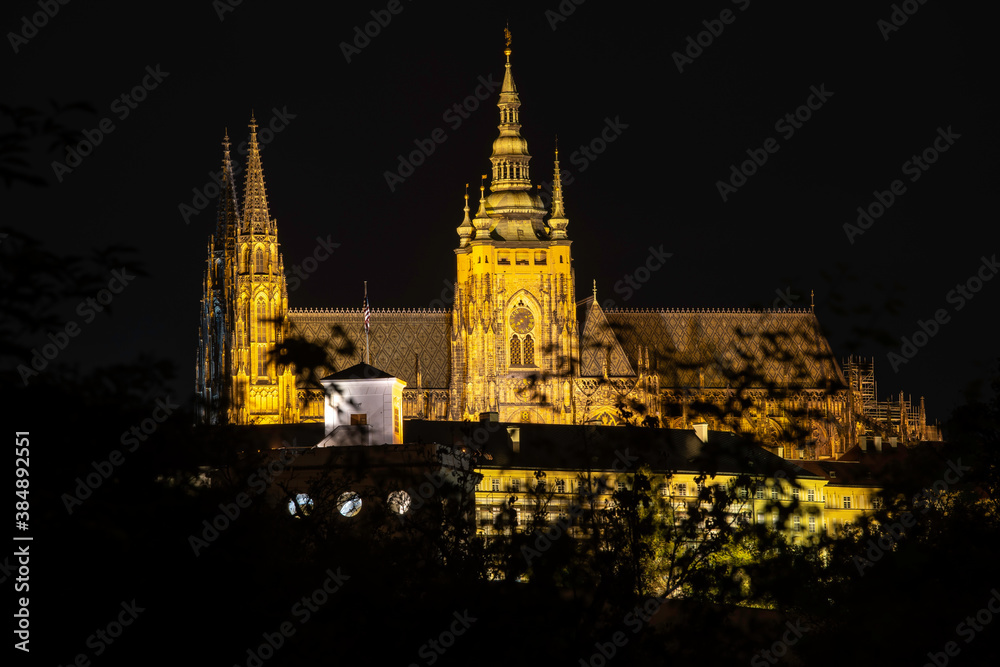 illuminated Vitus Cathedral and Prague Castle at night in the center of Prague. and reflections of lights on the flowing river Vltava in the town