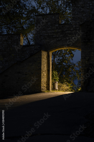 light from street lighting through the gate of the old wall from the 17th century in the center of Prague and a waste basket in a park in the Czech Republic at night