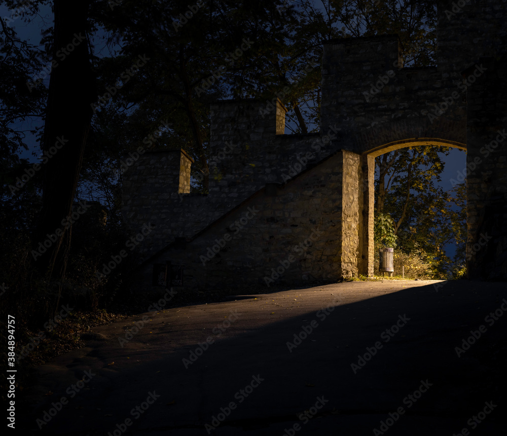 light from street lighting through the gate of the old wall from the 17th century in the center of Prague and a waste basket in a park in the Czech Republic at night light from street lighting through the gate of the old wall from the 17th century in the center of Prague and a waste basket in a park in the Czech Republic at night