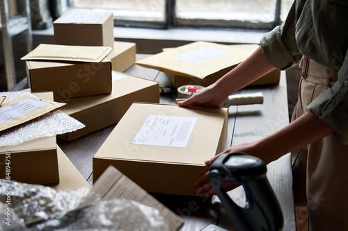 Female distribution warehouse worker or seller packing ecommerce shipping order box for dispatching, preparing post courier delivery package, dropshipping commerce retail shipment service concept. photo