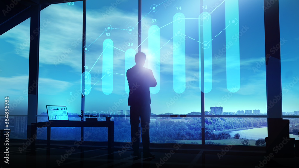 A businessman looks at a growth graph hologram at dusk. A businessman looks at a growth graph hologram at dusk.