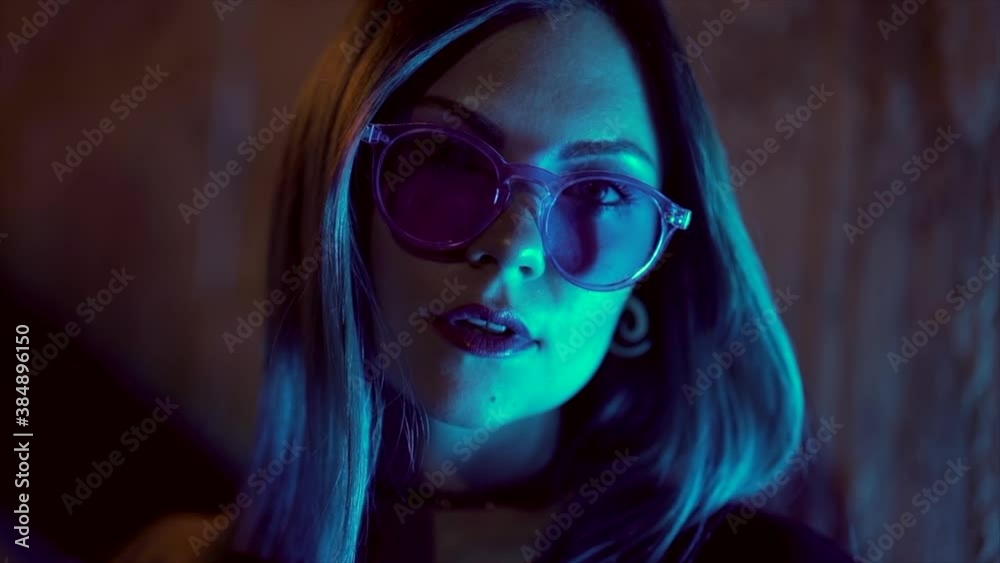 Portrait of millennial enigmatic pretty girl with unusual dyed blue hairstyle at night. Mysterious hipster woman in glasses. Portrait of millennial enigmatic pretty girl with unusual dyed blue hairstyle at night. Mysterious hipster woman in glasses.