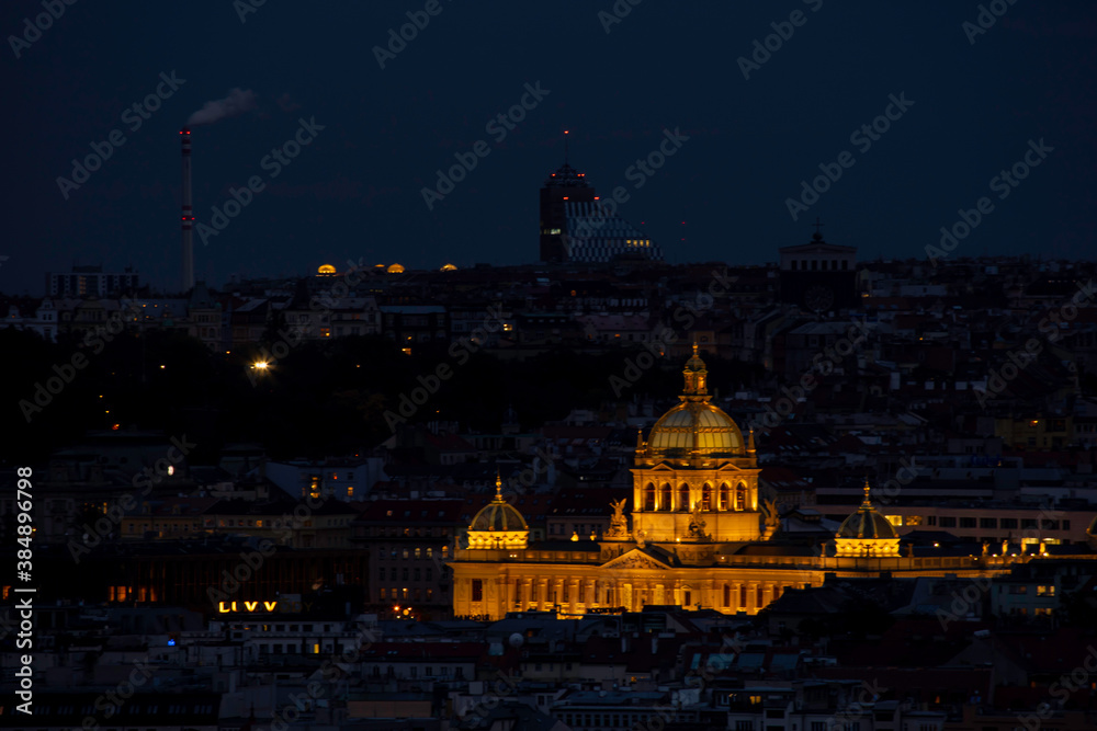 Fototapeta premium view of the roofs of buildings in the city of prague and the enlightened national museum from 1818 in the czech republic at night