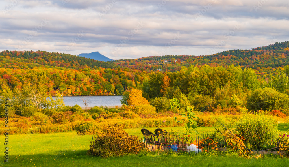 Lake Iroquois surrounded by forests in brilliant fall foliage colors with Camel's Hump Mountain in the distance 
