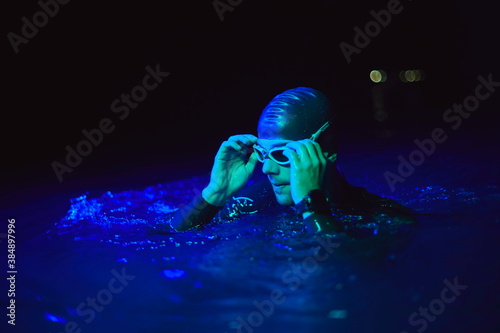 authentic triathlete swimmer having a break during hard training on night neon gel light