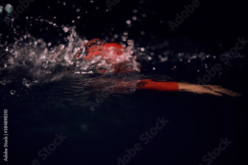 triathlon athlete swimming in dark night wearing wetsuit