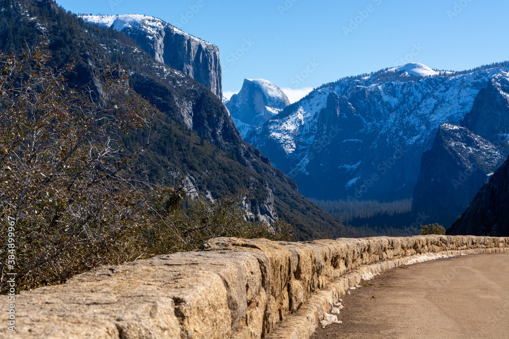 Rock Wall along Edge of Road in the Mountains at Yosemite Park with Blue Sky Background.