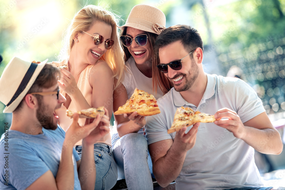Group of young people in the park eating pizza.