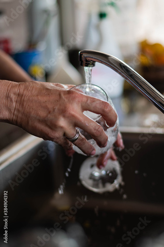 primer plano de manos lavando vajilla platos cubiertos copas de cristal esponja y jabon 